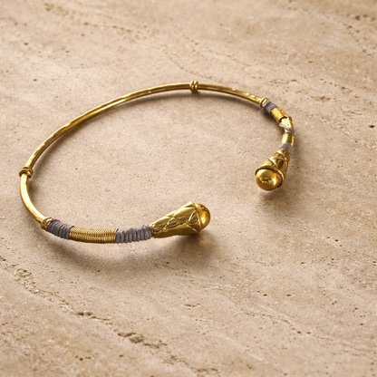Gold bracelet with decorative elements on a beige surface