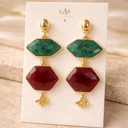 Pair of earrings with green and red gemstones on a display card.