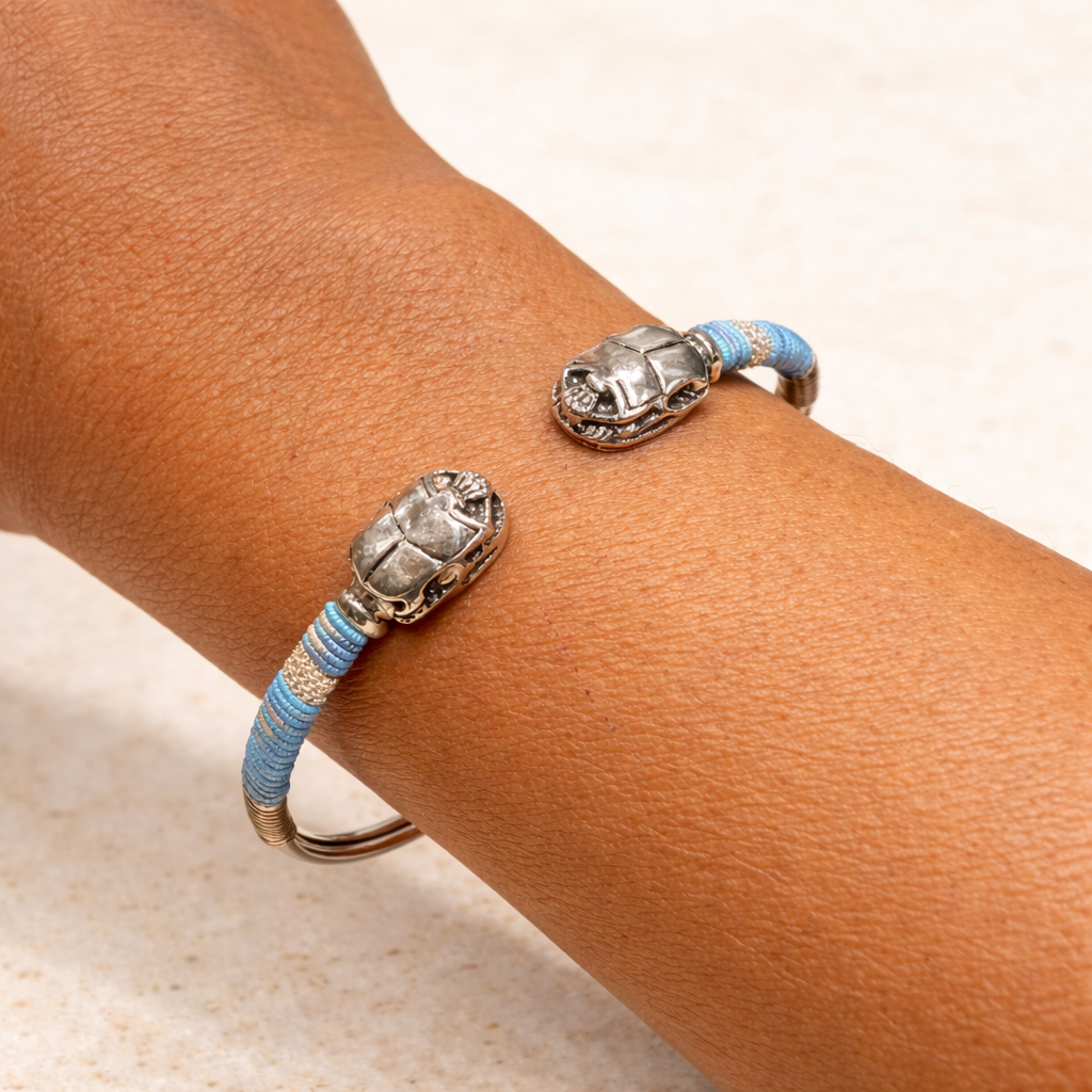 Bracelet with beetle design on a wrist against a neutral background