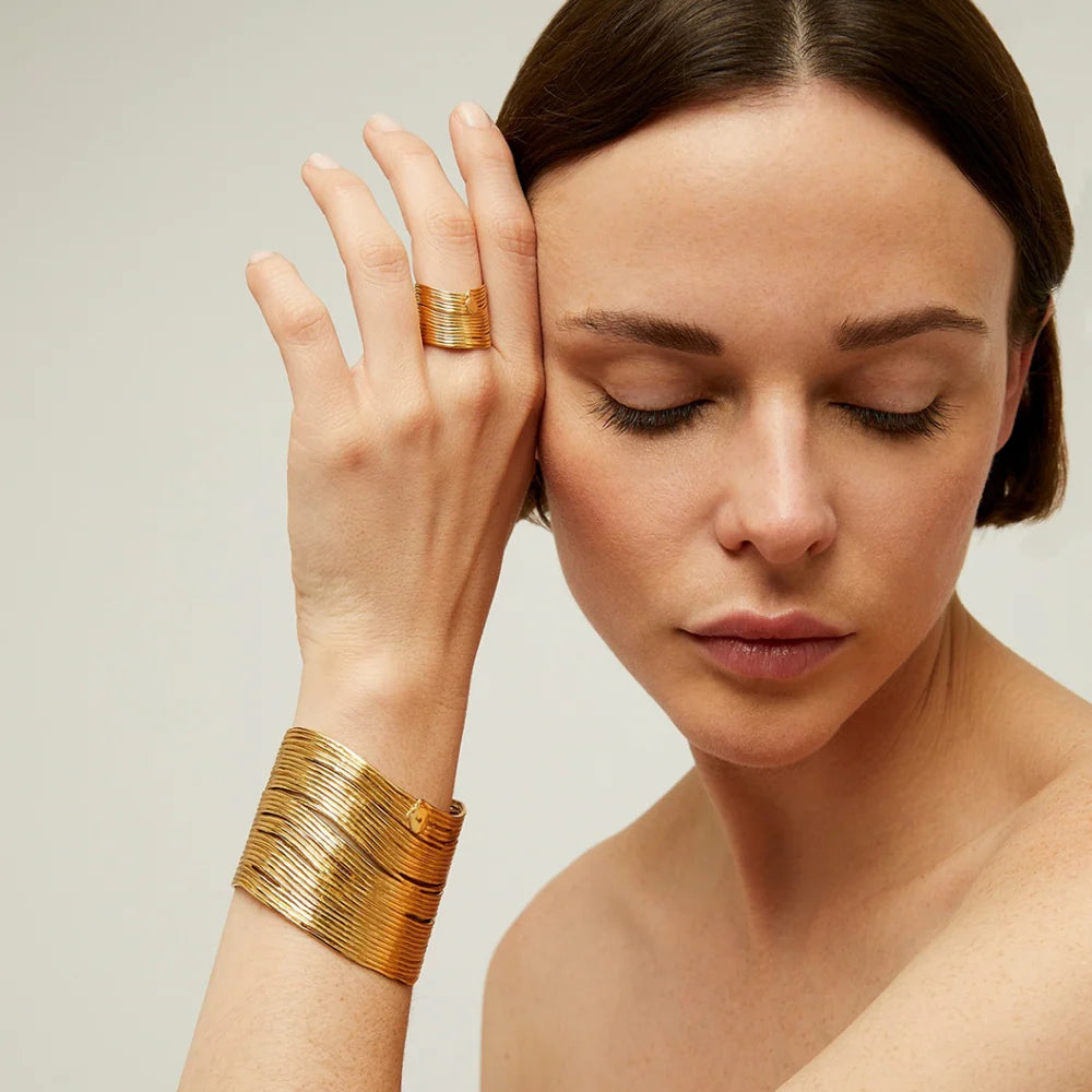Woman wearing gold jewelry on a neutral background