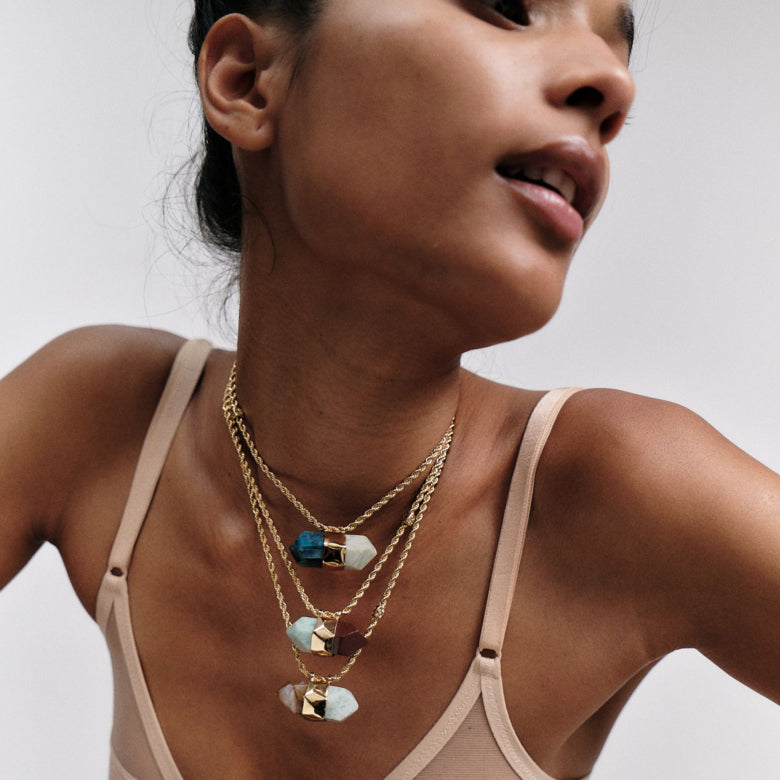 woman wearing layered stone necklaces in different colours and lengths against a neutral background