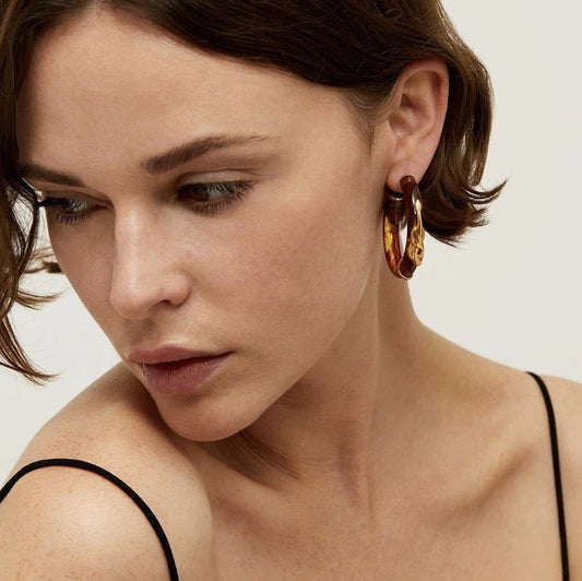 woman wearing brown and gold hoops on a cream background