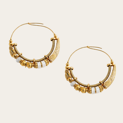 Gold hoop earrings with white beads on a white background