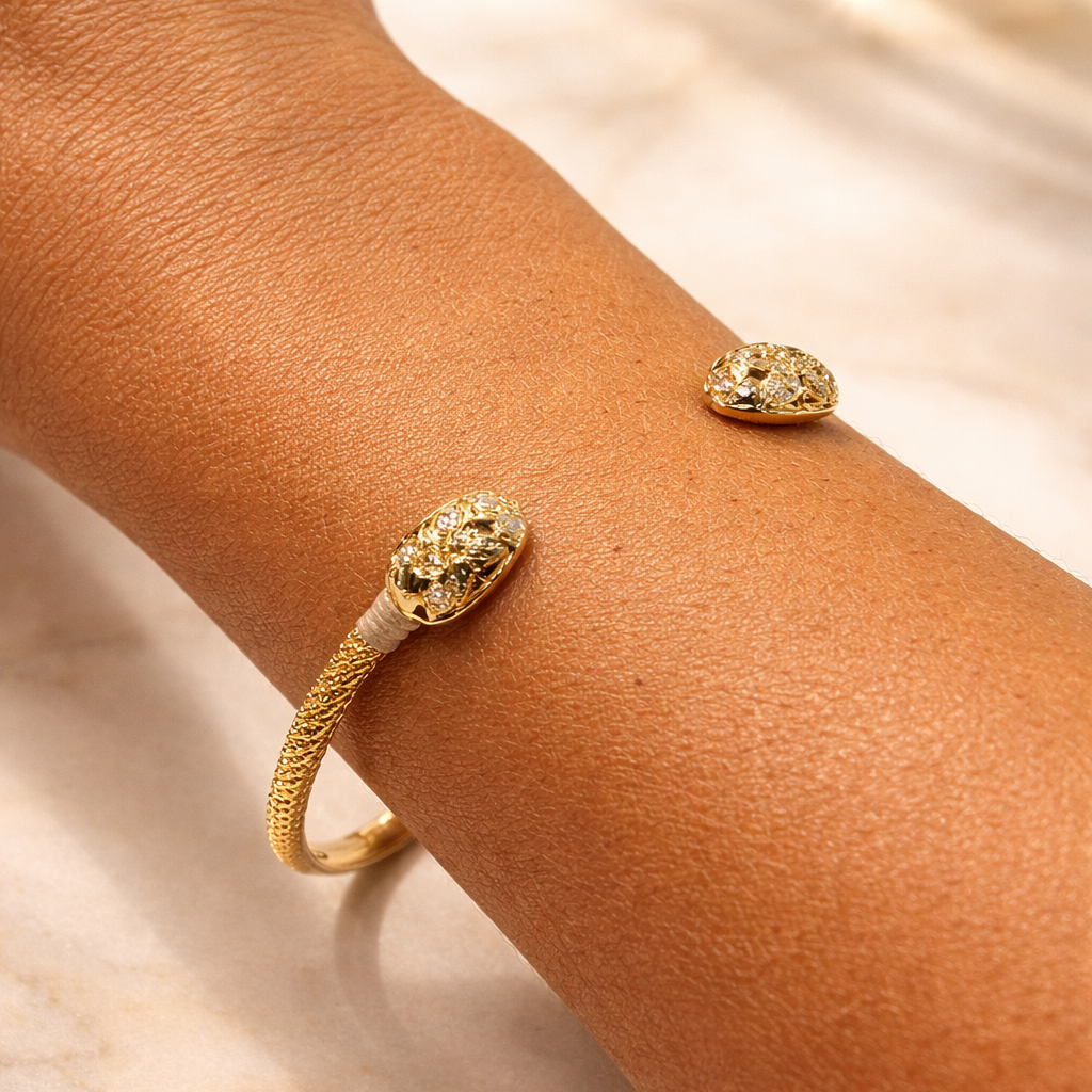 Gold bracelet with snake design on a wrist against a light background