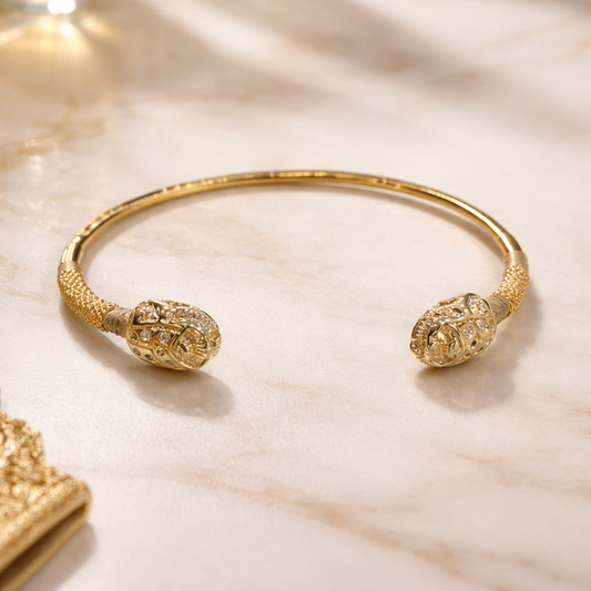 Gold bracelet with intricate design on a marble surface
