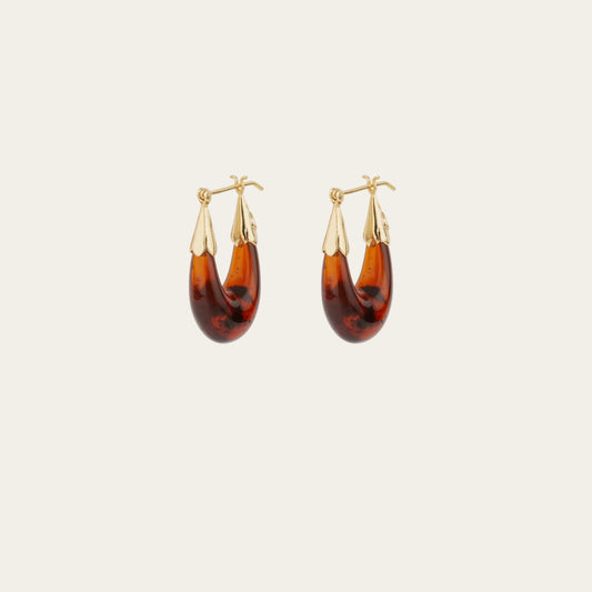 Pair of tortoiseshell hoop earrings with gold accents on a light beige background