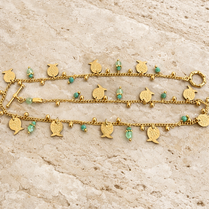 gold necklace with fish charms on travertine surface