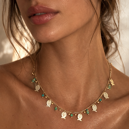 close up of gold and turquoise necklace with fish charms on woman neck