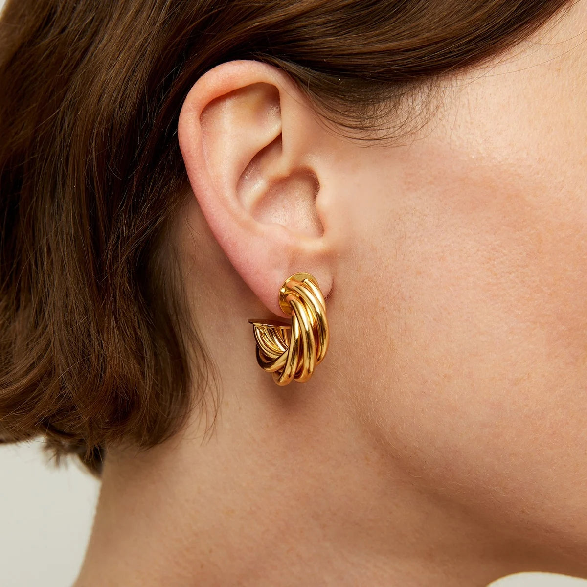 Gold twisted earrings close up on ear