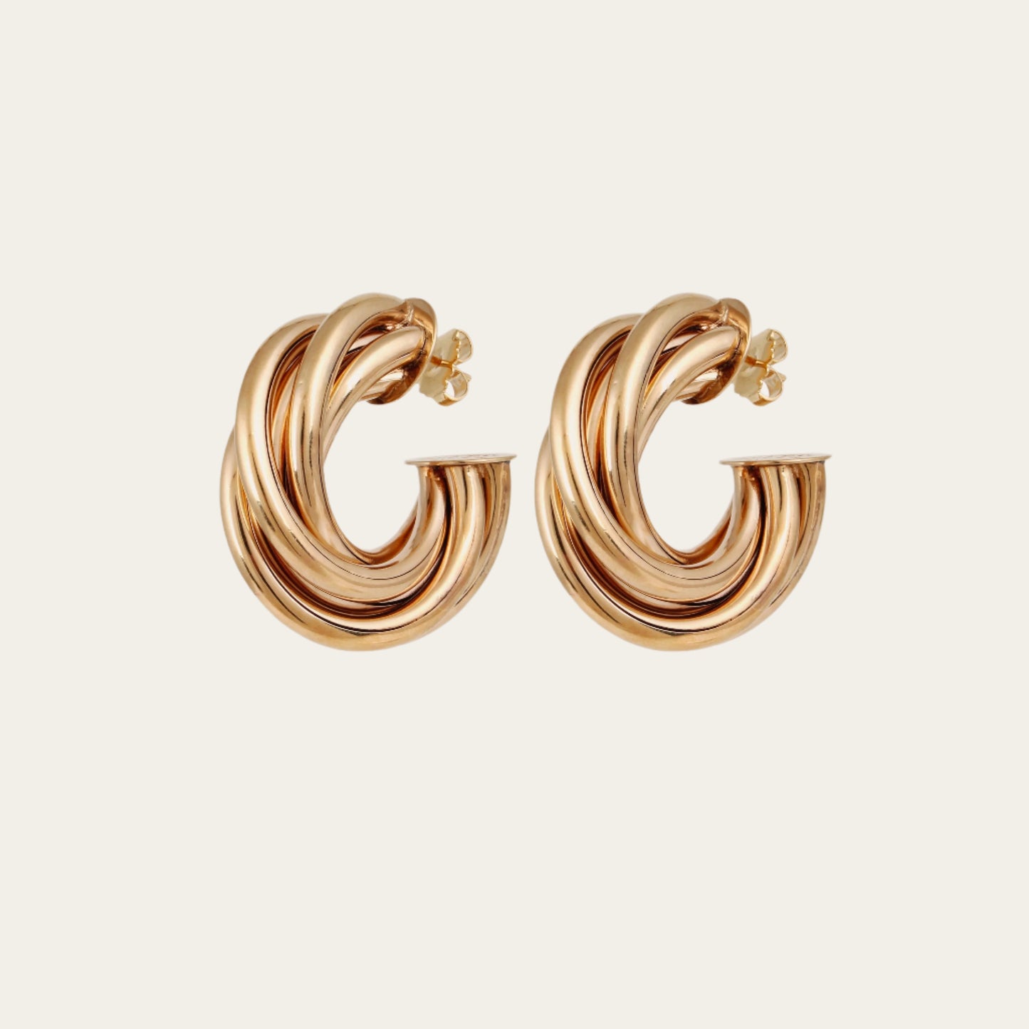 Gold hoop earrings on a light beige background