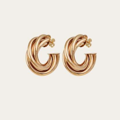 Gold hoop earrings on a light beige background