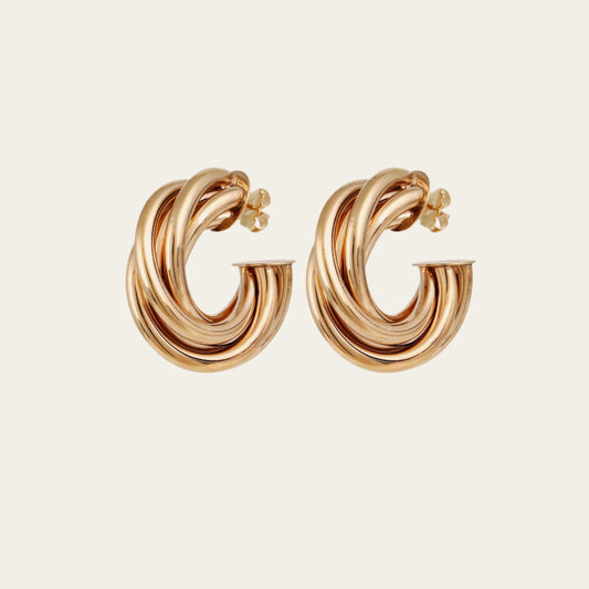 Gold hoop earrings on a light beige background