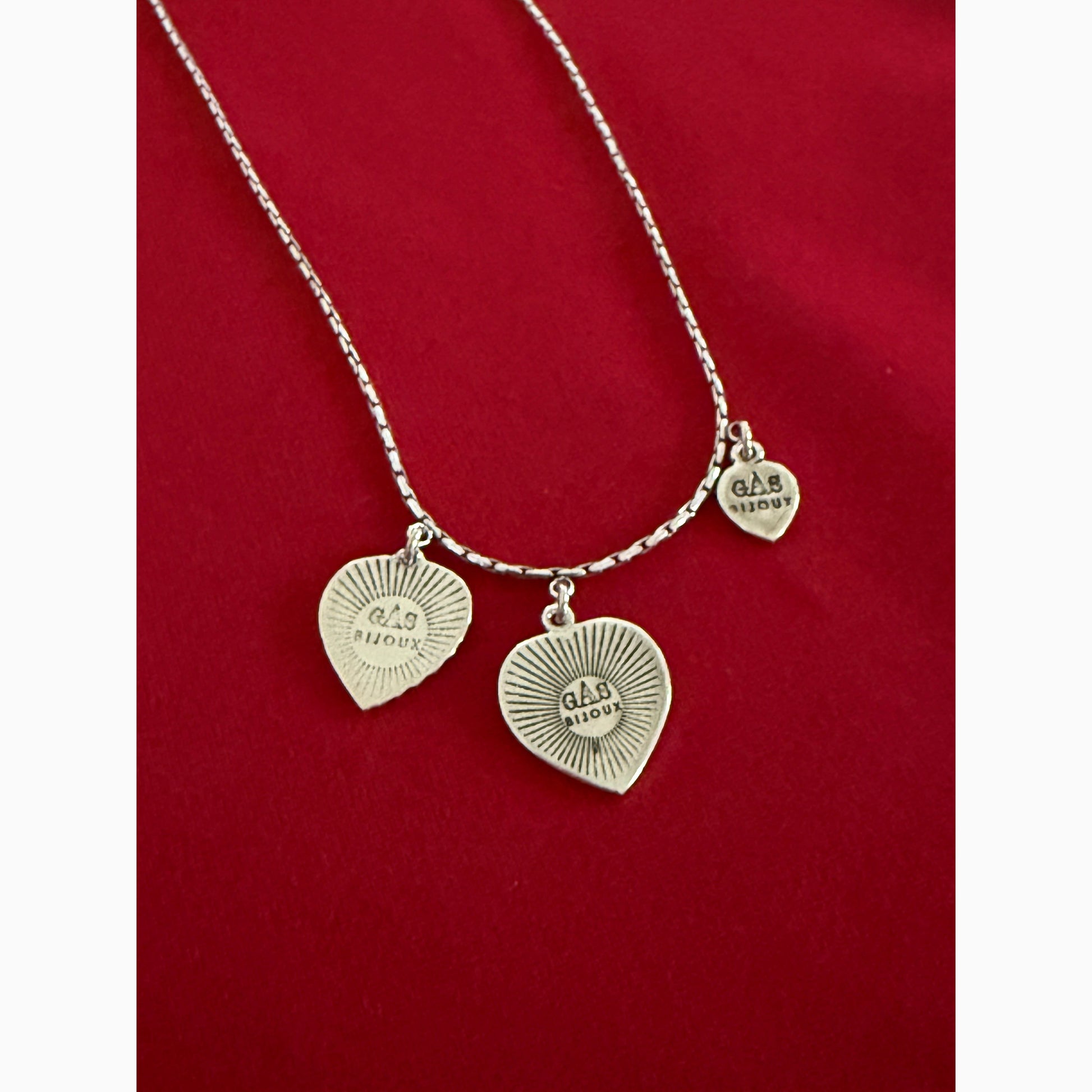 Silver bracelet with heart-shaped charms on a red background