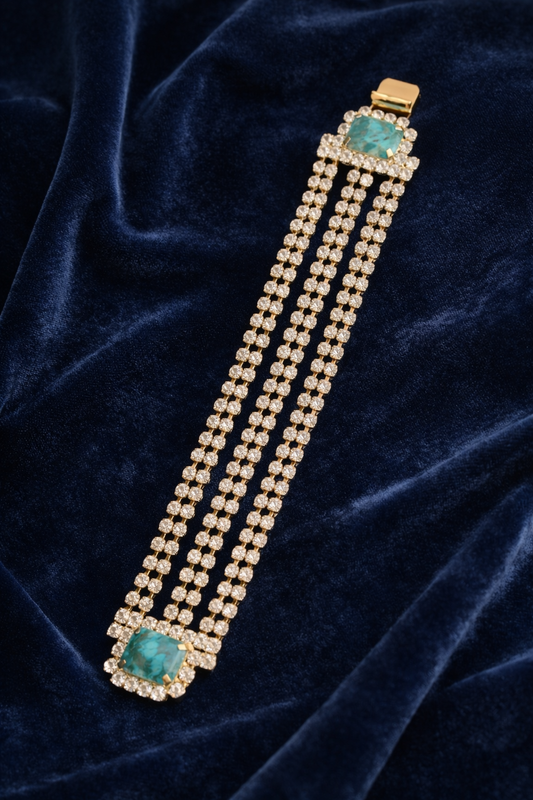 Bracelet with turquoise stones and gold accents on a dark blue velvet background