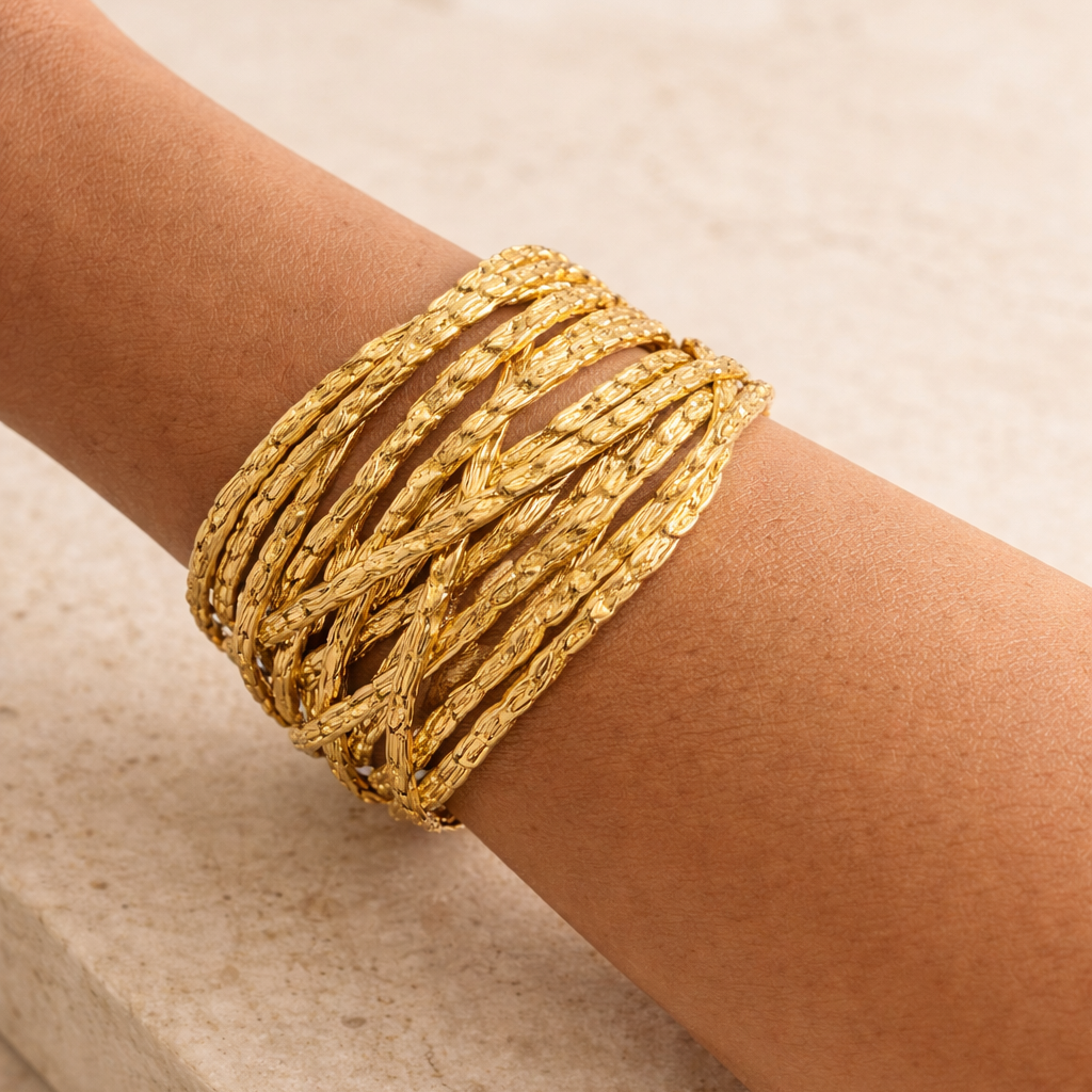 Gold bracelet on a person's wrist against a beige background