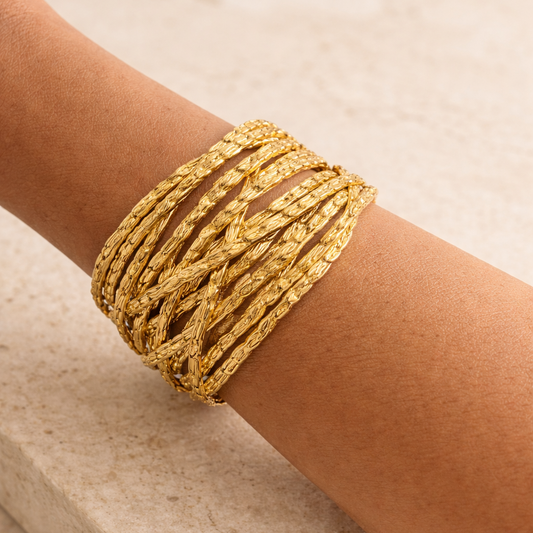 Gold bracelet on a person's wrist against a beige background