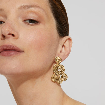 gold hand hammered dangle earrings on a woman