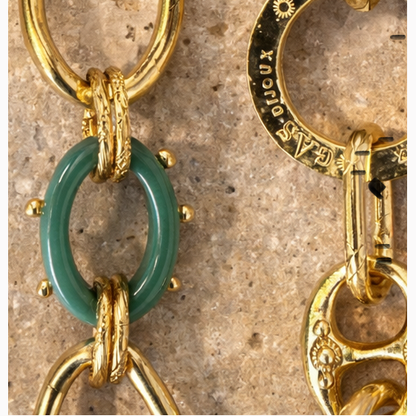 Close-up of gold and green chain necklace on a textured surface