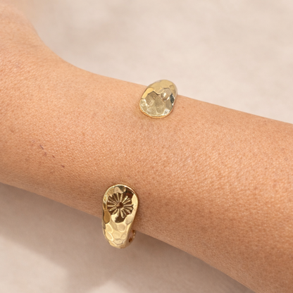 Gold bracelet  on a wrist against a neutral background