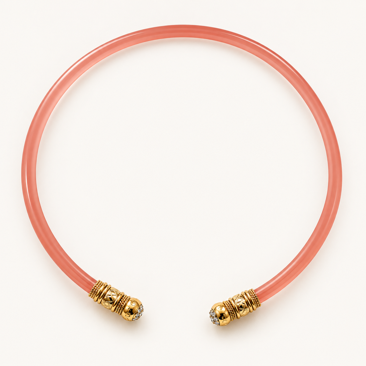 A translucent coral pink necklace choker with textured gold-toned end caps, photographed on a clean off-white background.