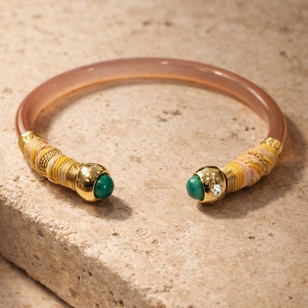 Bracelet with gold and green beads on a beige stone surface