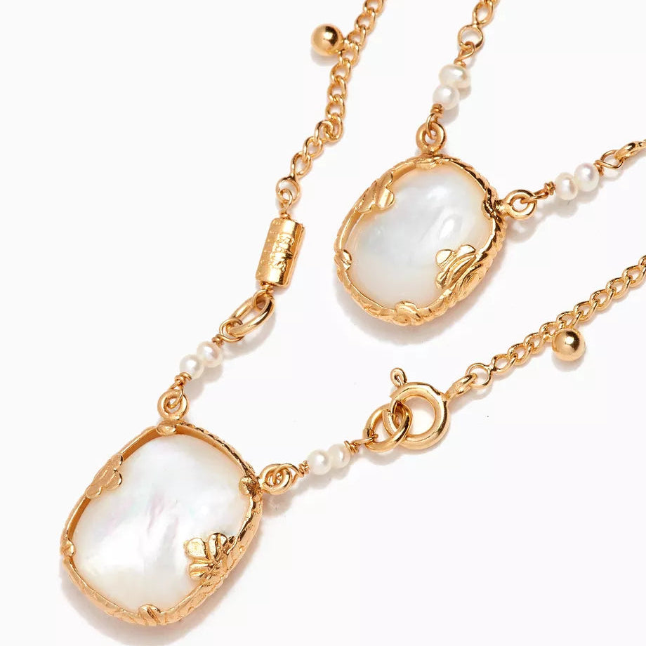 Gold necklace with pearl pendants on a white background