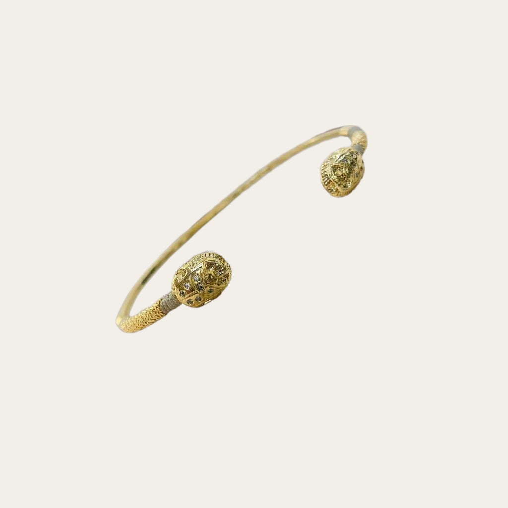 Gold Bangle with grey thread and precious stones on light background