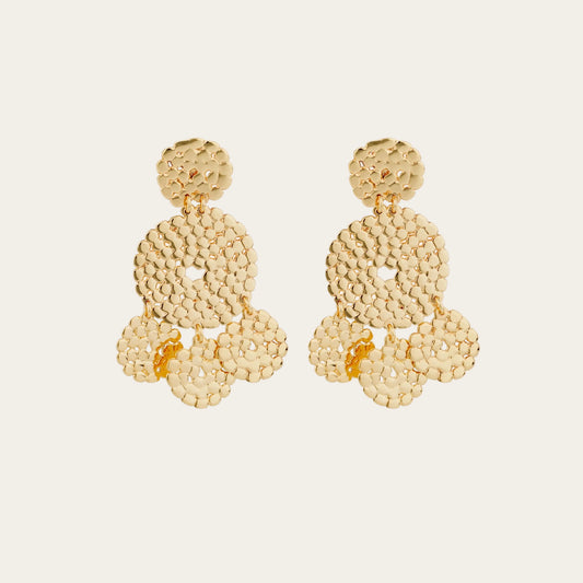 Gold hand hammered earrings on a light beige background