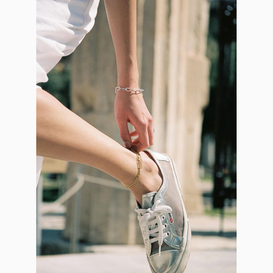 Person wearing an anklet white sneaker with a blurred background