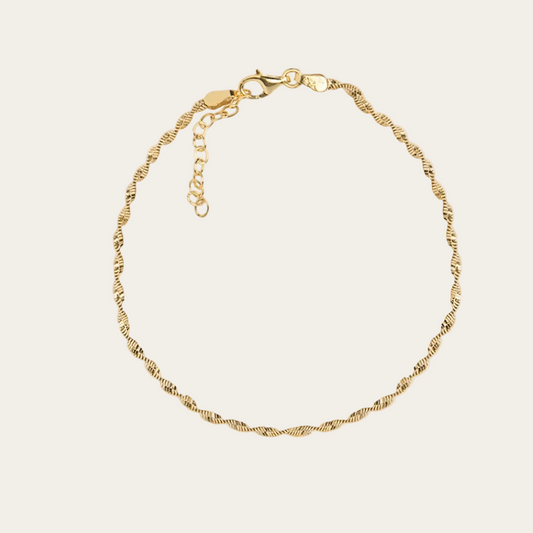 Gold anklet on a beige background