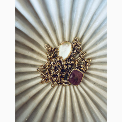 Gold and red gemstone brooch on a textured white background