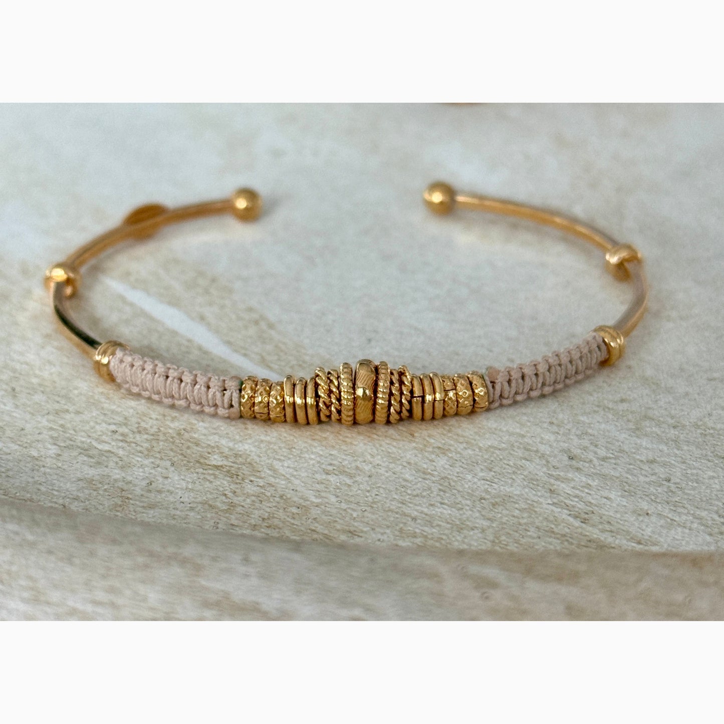Gold bracelet with textured design on a light stone surface