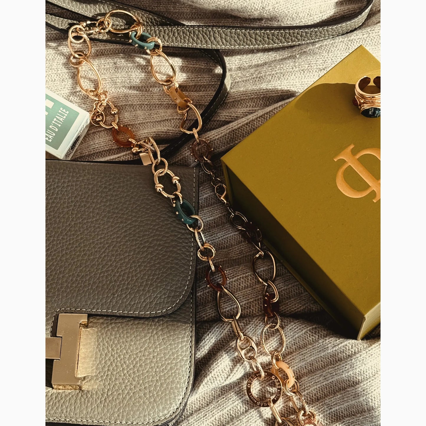 Gold chain necklace on a handbag with a gold box in the background