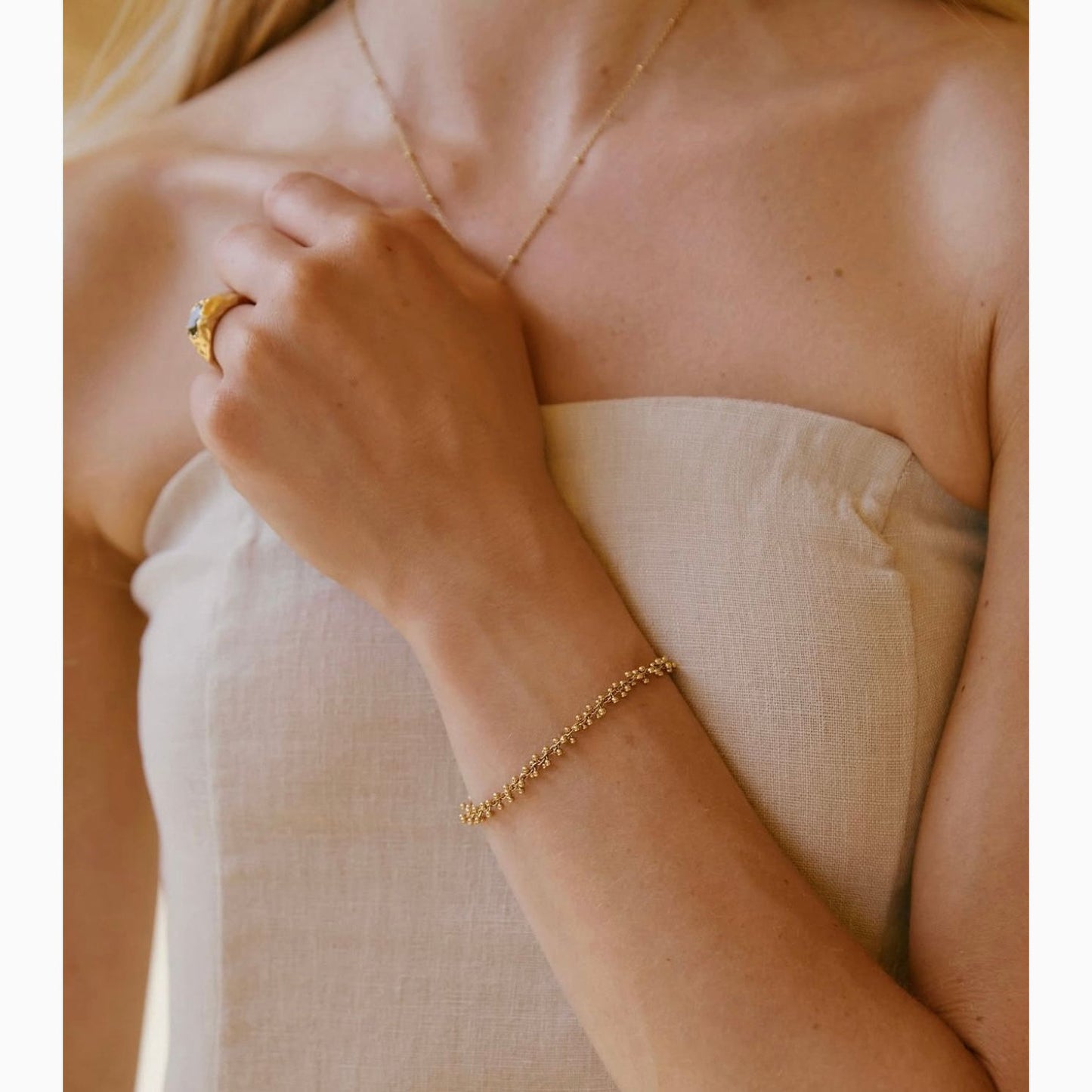 Close-up of a person wearing gold jewelry including a ring and bracelet.