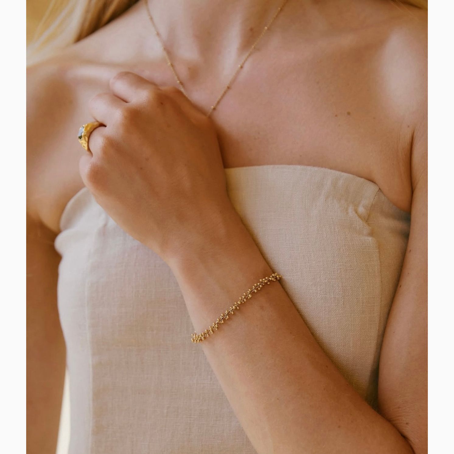 Close-up of a person wearing gold jewelry including a ring and bracelet.