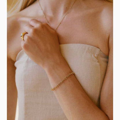 Close-up of a person wearing gold jewelry including a ring and bracelet.