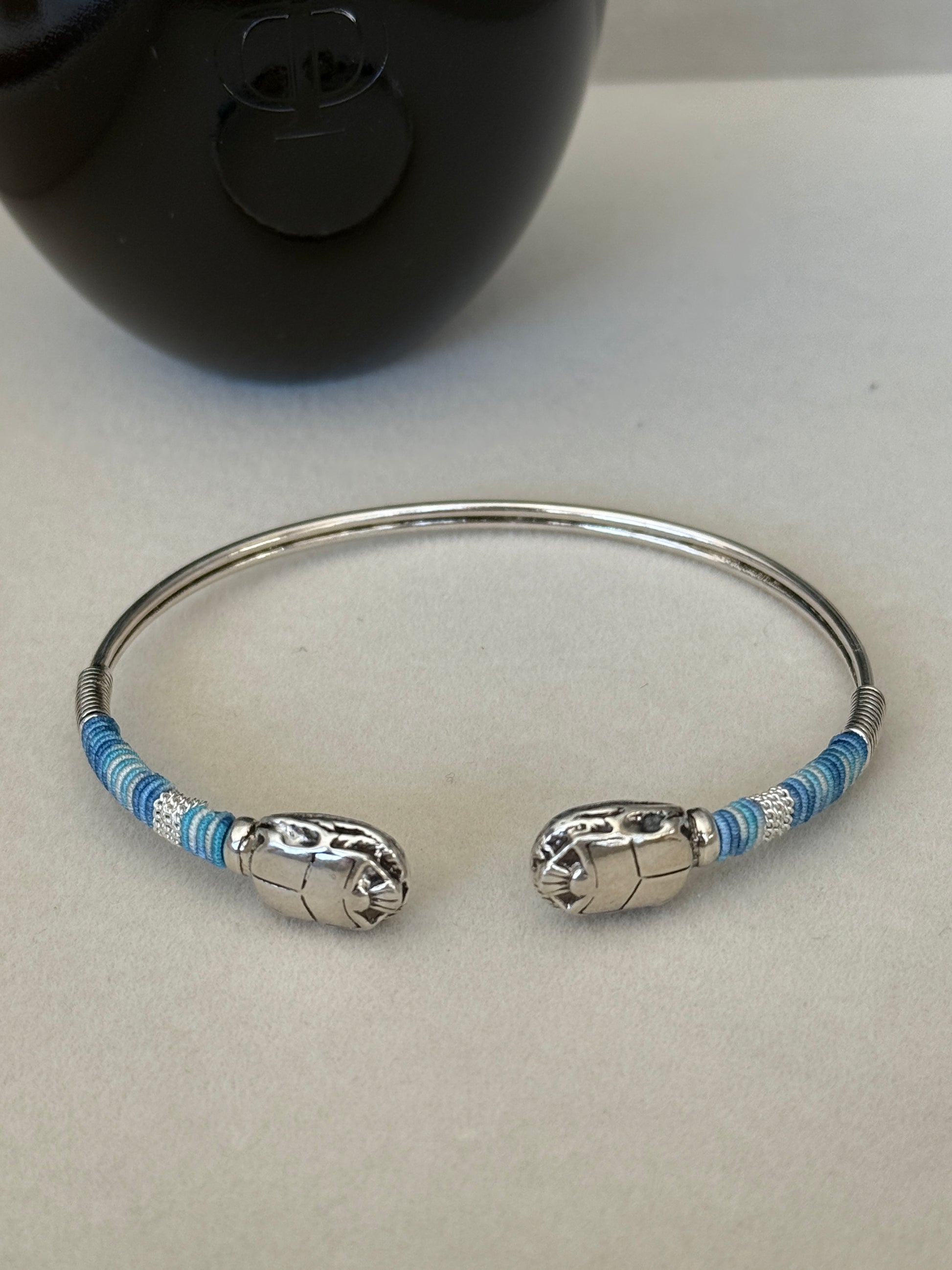 Silver bracelet with blue accents on a light gray background