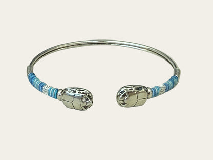 Silver bracelet with blue threads on a light gray background