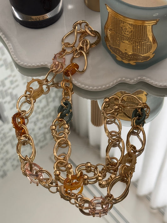 Lifestyle image of gold and resin necklace on mirror surface