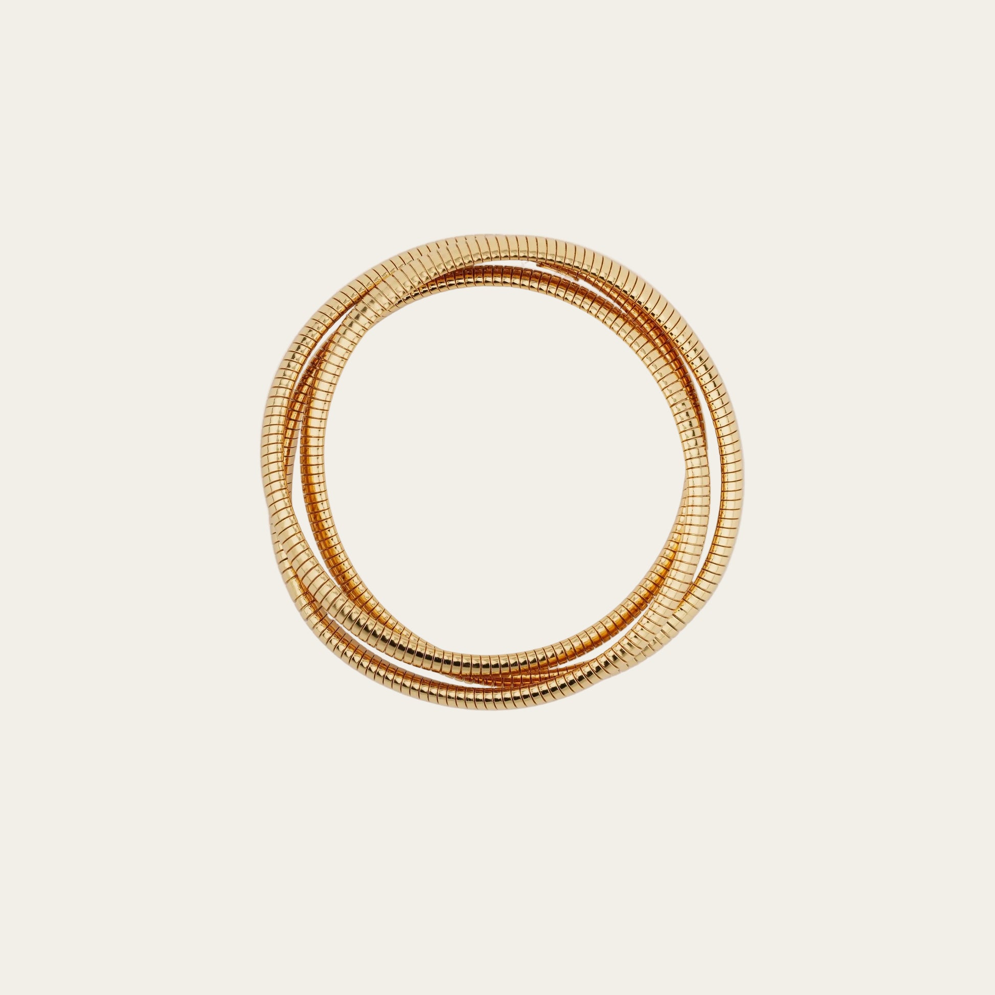Set of gold bangles on a light beige background