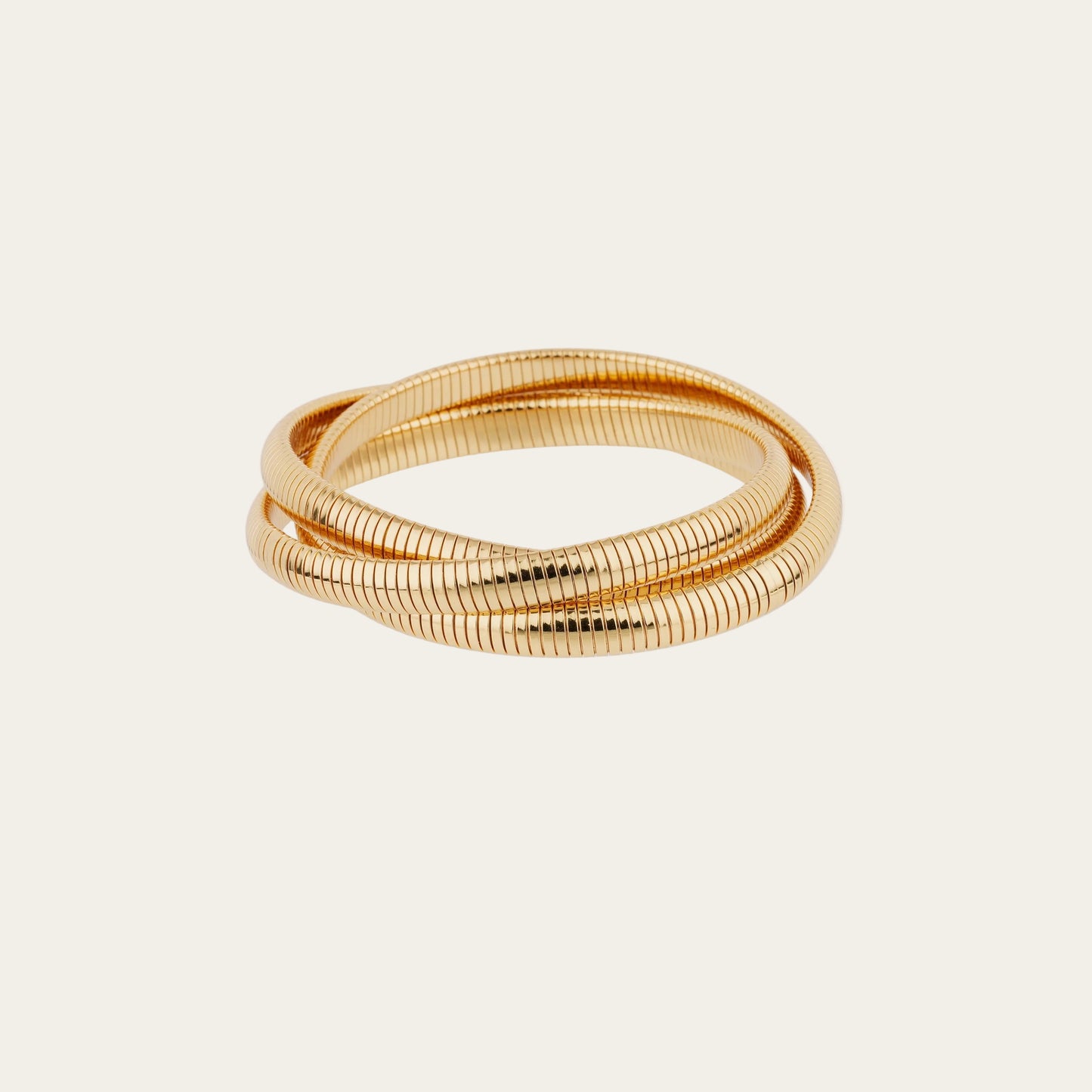 Gold bracelet with a textured design on a light beige background