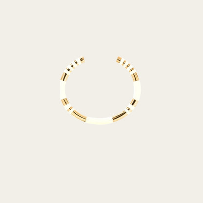 A white and gold bangle bracelet with a simple, elegant design featuring ivory stripes and gold accents.