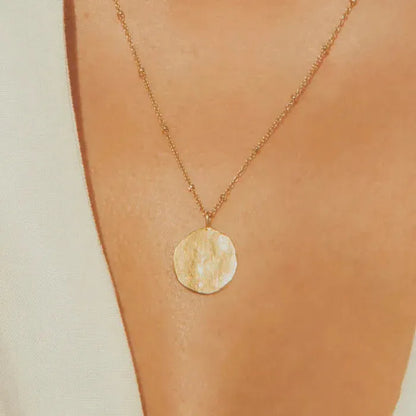 Minimalist and delicate, this necklace feels like a precious ancient vestige. Its hammered full moon design will protect you day and night.