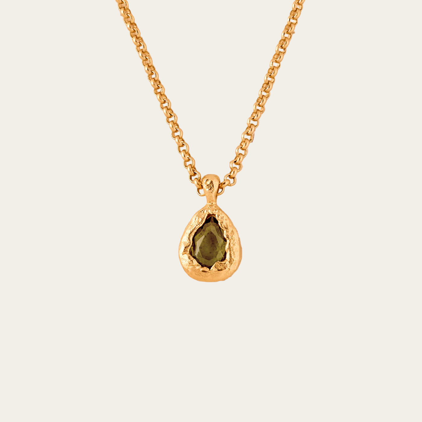 gold necklace with green pendant stone on neutral background