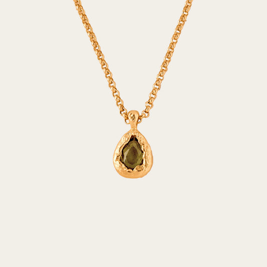 gold necklace with green pendant stone on neutral background