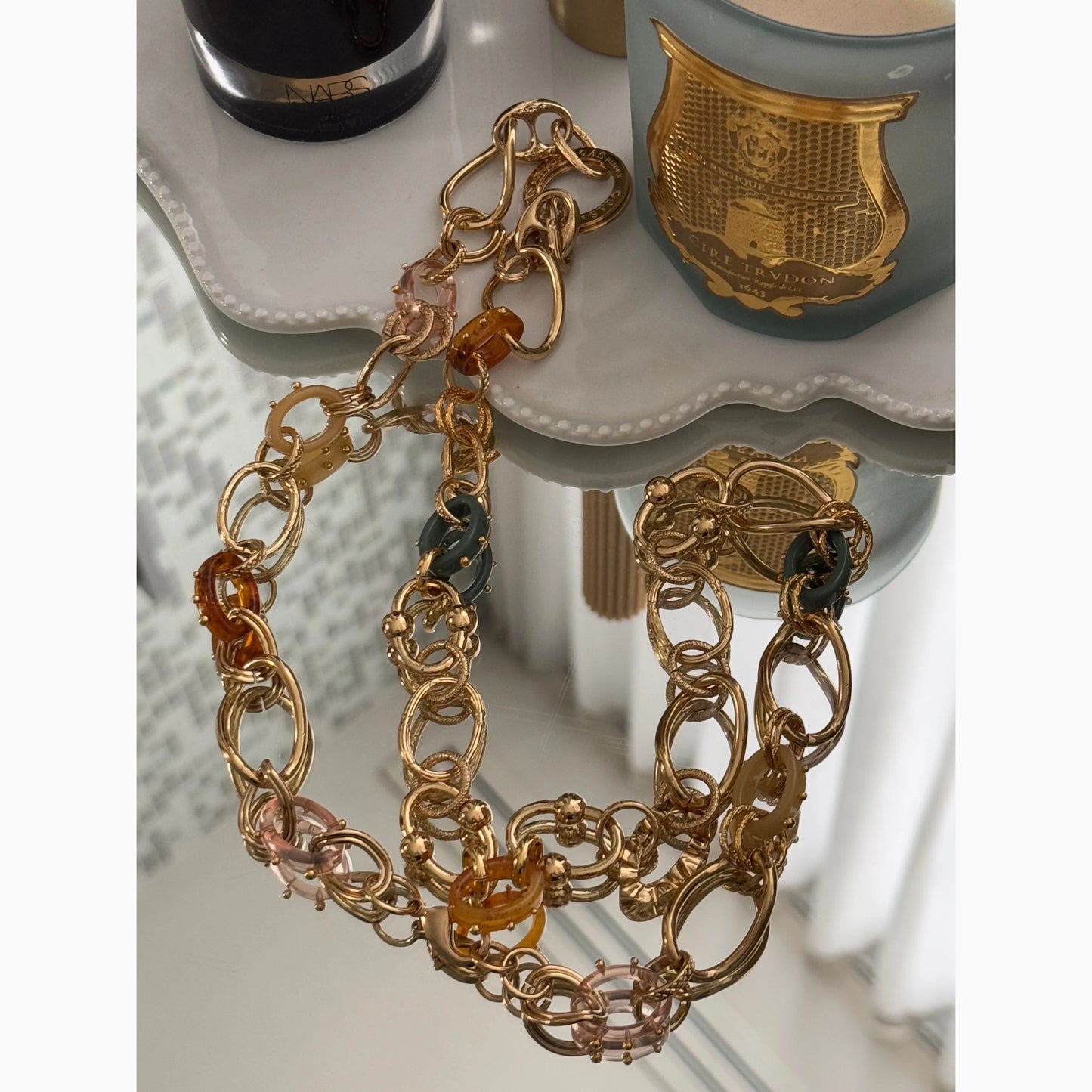 Lifestyle image of gold and resin necklace on mirror surface