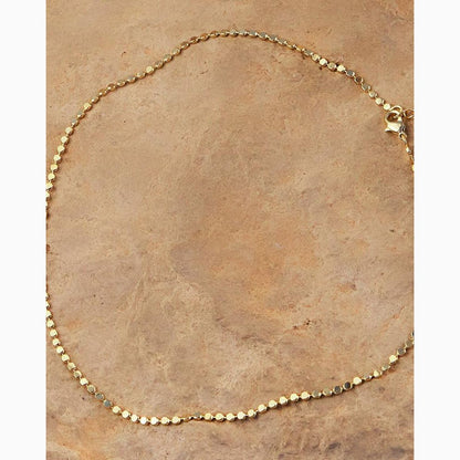 Gold necklace on a textured brown surface