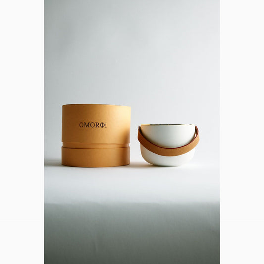 Ceramic bowl with brown rim and white interior next to a matching orange cylindrical container on a light gray background.