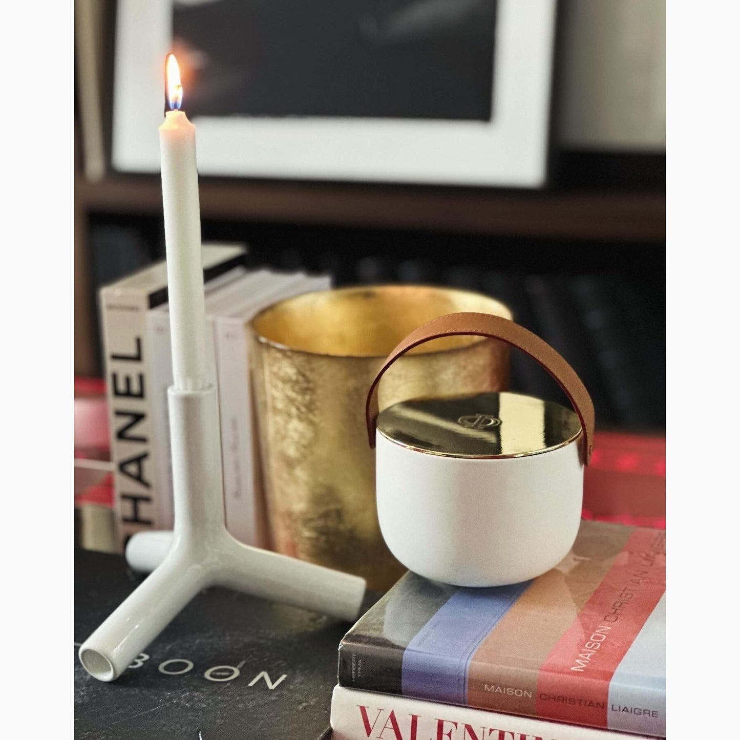 ceramic candle with gold lid surronded by books and pillar candle
