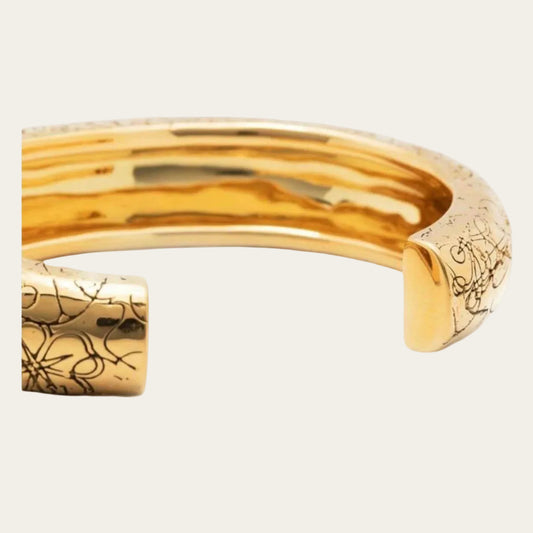 Rosalba gold cuff with intricate detail on flat lay